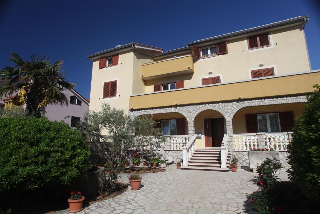 a large building with stairs and a palm tree at Cres Sučić Apartments in Cres