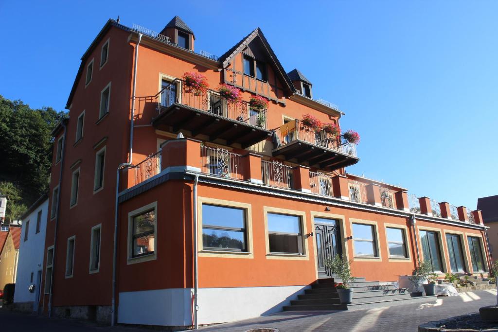 ein orangefarbenes Gebäude mit Balkonen und Blumen darauf in der Unterkunft Dampfschiffhotel in Stadt Wehlen