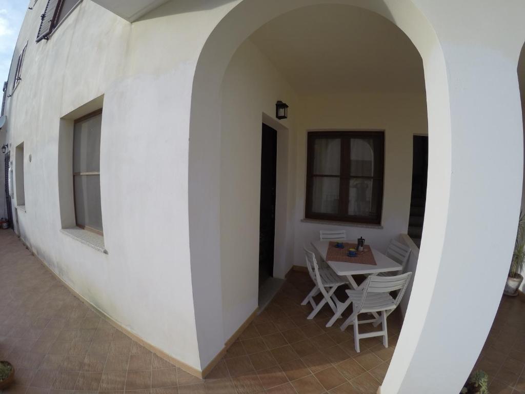 una stanza con tavolo, sedie e parete bianca di Appartamenti a 500 metri dal mare a Santa Maria Navarrese