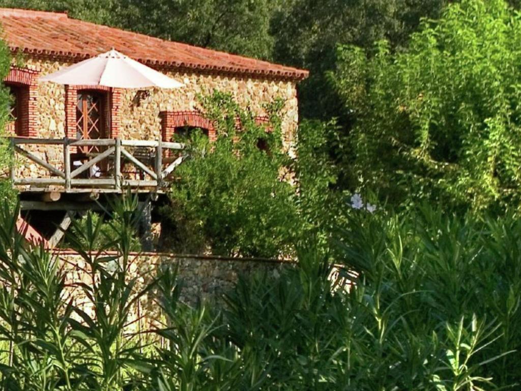 a person sitting at a table with an umbrella at Tranquil Riverside Retreat in Alájar