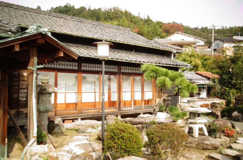 a japanese house with a garden in front of it at Guest House Toranjyo-lit in Tamano