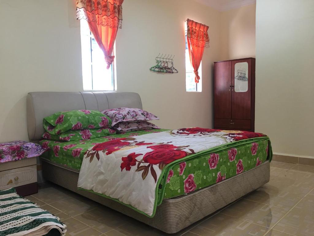 a bedroom with a large bed with green and red sheets at Homestay d SOFIA in Kuala Terengganu