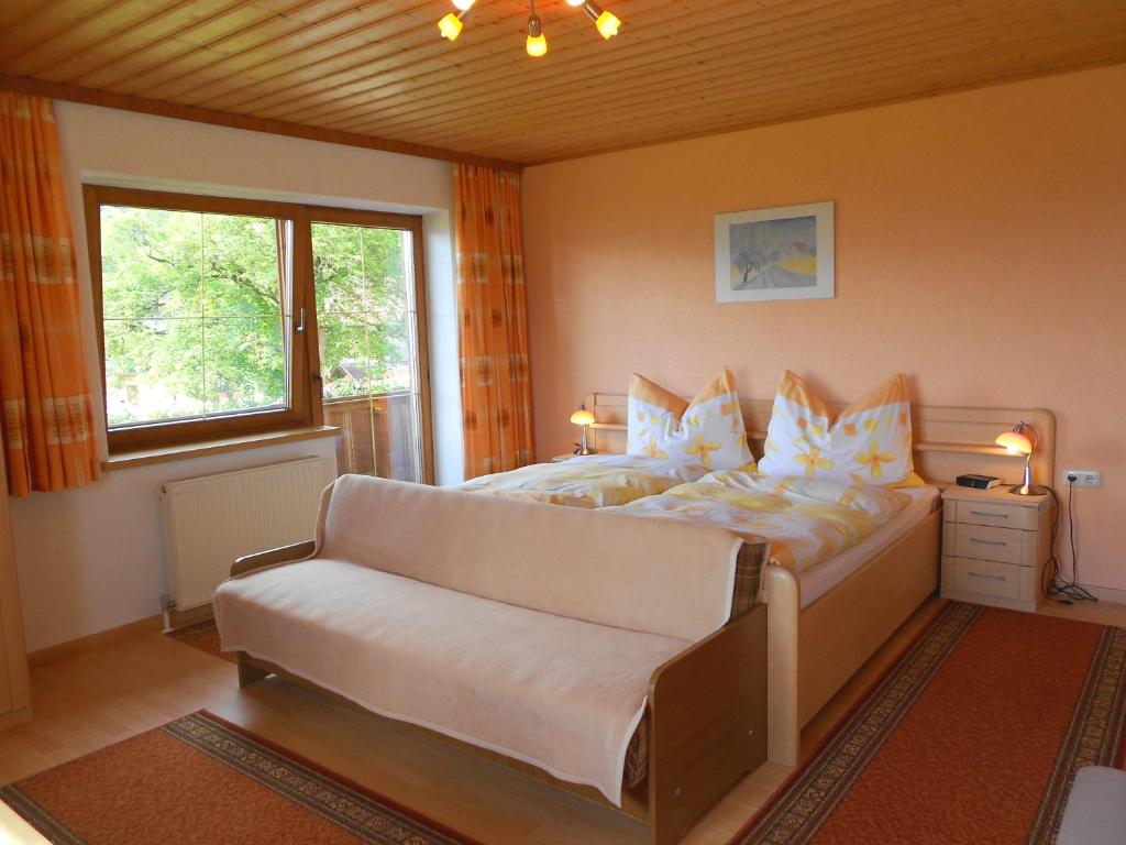 a bedroom with a bed with a couch and a window at Haus Schweigl in Obsteig