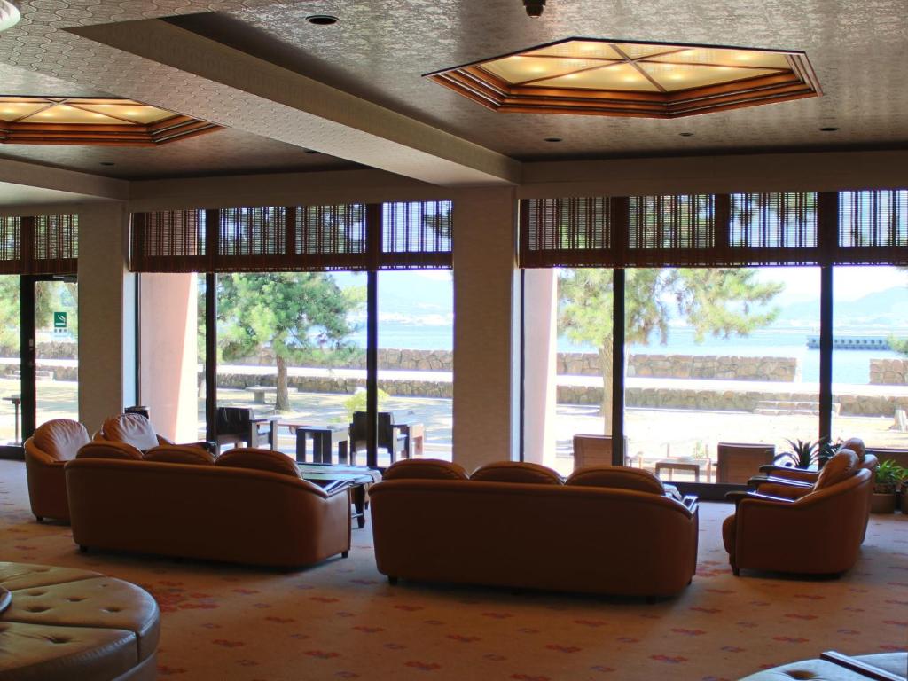 a waiting room with couches and tables and windows at Miyajima Seaside Hotel in Miyajima