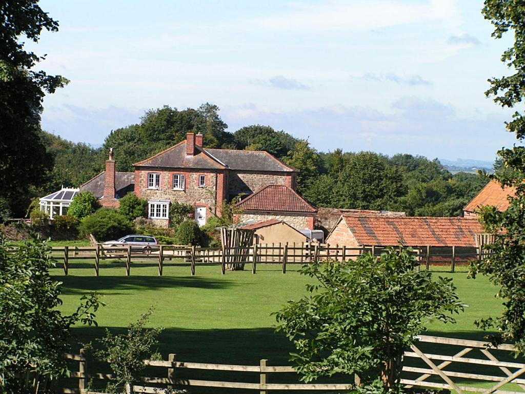 una casa grande con una valla y un campo verde en Blounts Court Farm, en Devizes