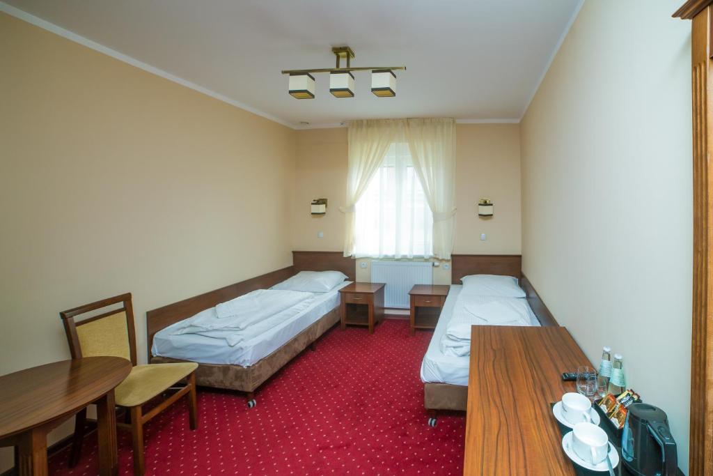 Habitación de hotel con 2 camas y mesa de comedor en Hotel Grant, en Leszno
