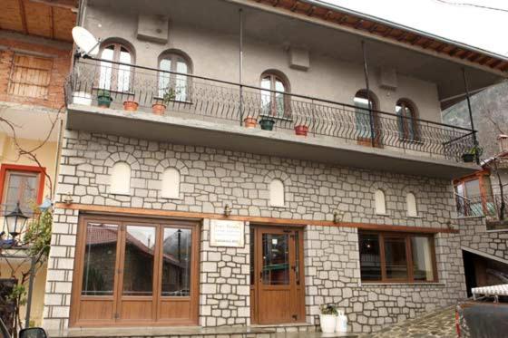 een bakstenen gebouw met een balkon erboven bij Anilio Rooms in Anilio Metsovo