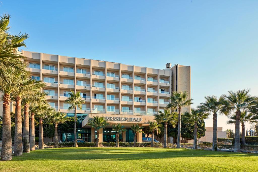 un hôtel avec des palmiers devant lui dans l'établissement Grecian Park, à Protaras