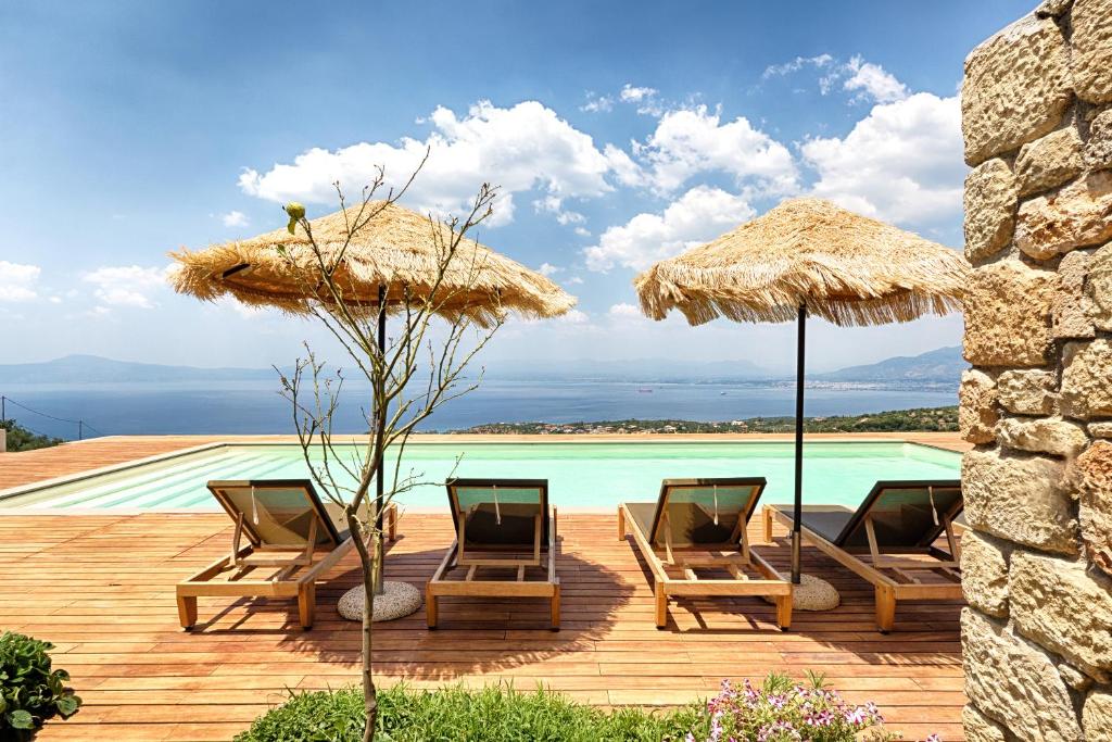 two chairs and umbrellas next to a swimming pool at Euphoria Suites in Avía