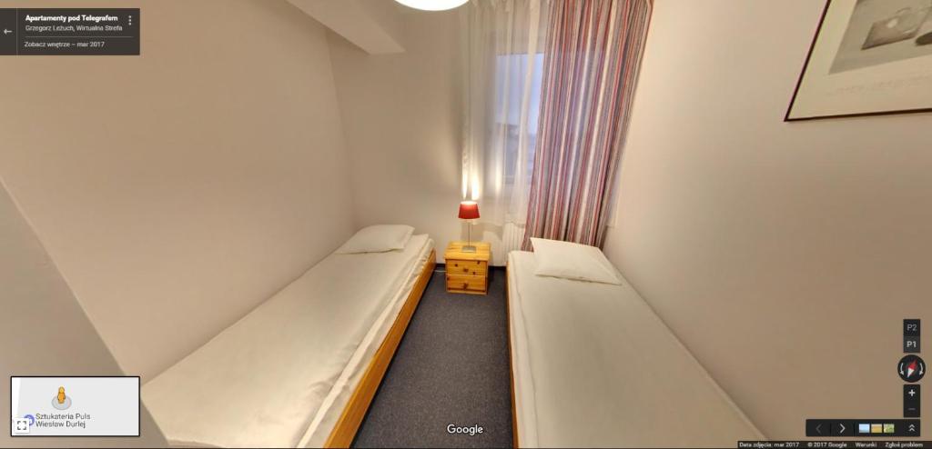 a small room with two beds and a lamp at Apartamenty Pod Telegrafem in Kielce