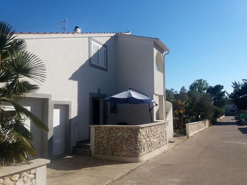 um edifício branco com um guarda-chuva em frente em Noa em Vodice