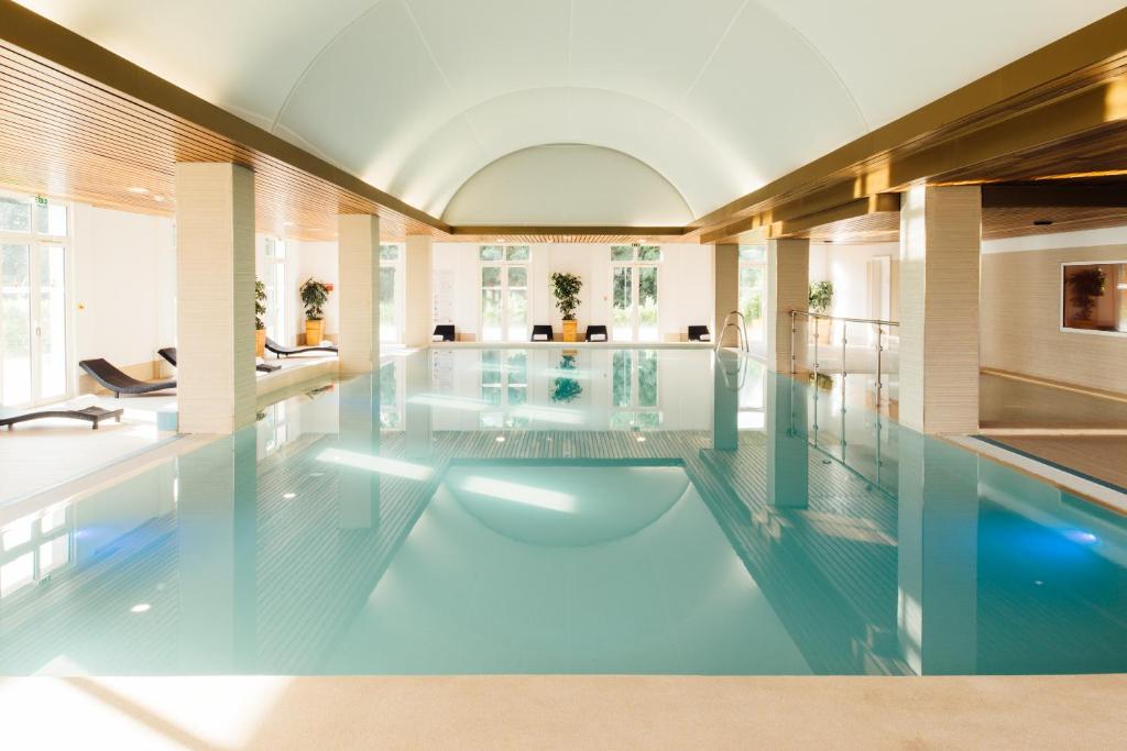 ein großer Pool mit blauem Wasser in einem Gebäude in der Unterkunft Grand Magic Hotel Marne La Vallée in Magny-le-Hongre