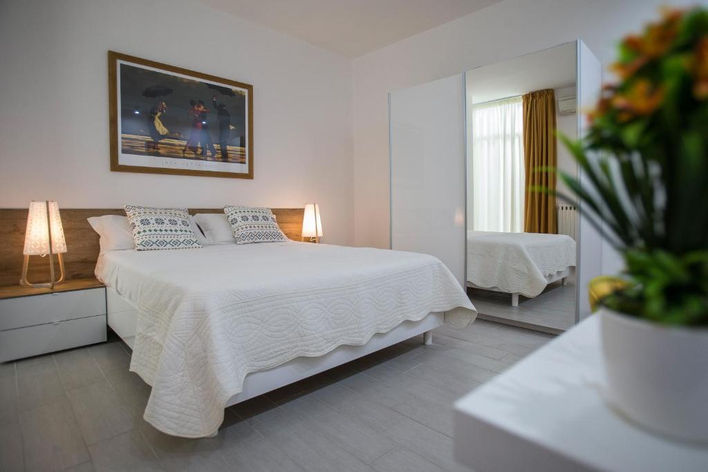 - une chambre avec un grand lit blanc et un miroir dans l'établissement B&B Sapore di Sale con parcheggio ed ombrellone in spiaggia, à Porto Cesareo