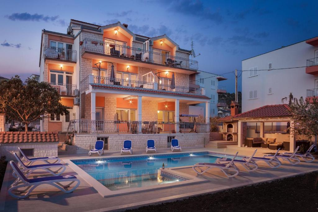 a house with a swimming pool in front of a house at Apartments Villa Matijas in Poljica