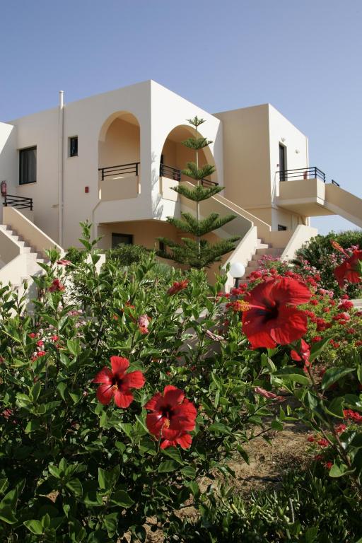 a house with red flowers in front of a building at Nanakis Beach Apartments in Stavros