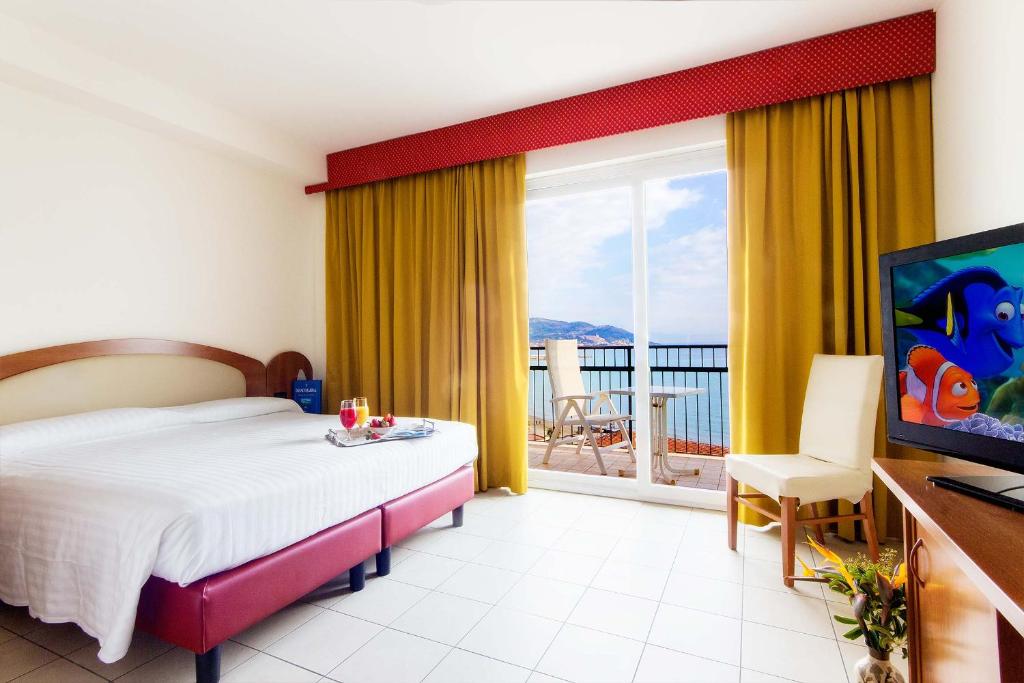 a bedroom with a bed and a television and a balcony at Piccolo Hotel in Diano Marina