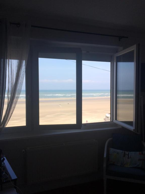een kamer met een raam met uitzicht op het strand bij Les Chambres d'Hôtes de la Mer in Merlimont