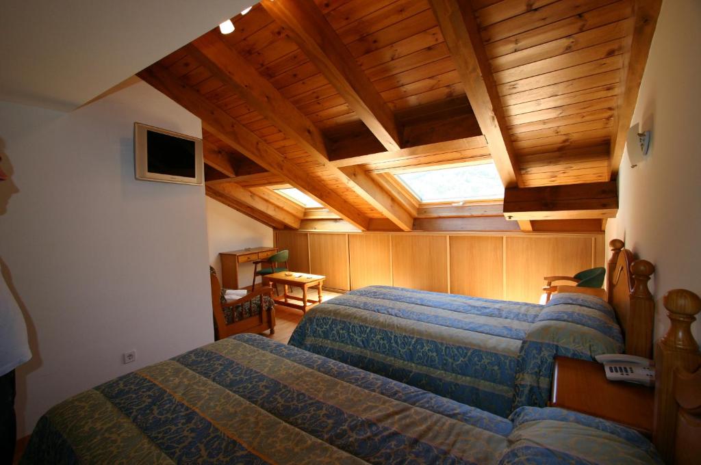 a bedroom with two beds and a wooden ceiling at Hotel Can Mestre in El Pont de Suert