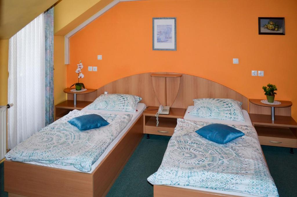 2 Betten in einem Zimmer mit orangefarbenen Wänden in der Unterkunft Penzion Gostilna Keber in Domžale