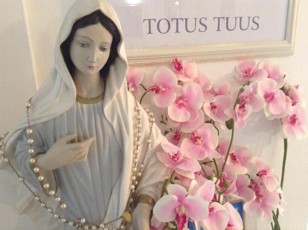 a religious statue of a woman next to pink flowers at St Michael in Međugorje