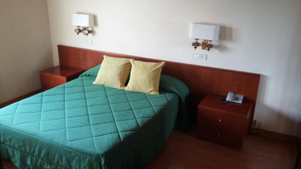 ベイベル・デ・サルダーニャにあるHotel Bon Reposのベッドルーム1室(緑のベッド1台、ナイトスタンド2台付)