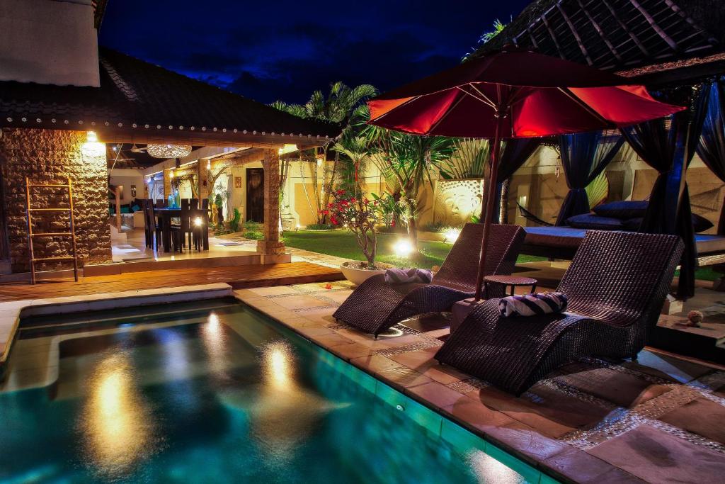 a swimming pool with two chairs and an umbrella at La Bella Vita Residence in Seminyak
