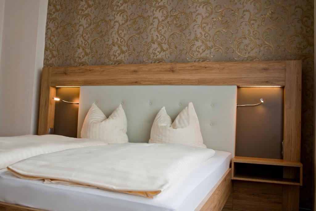1 dormitorio con 1 cama con sábanas y almohadas blancas en Weinhotel Römerbad, en Bad Salzuflen