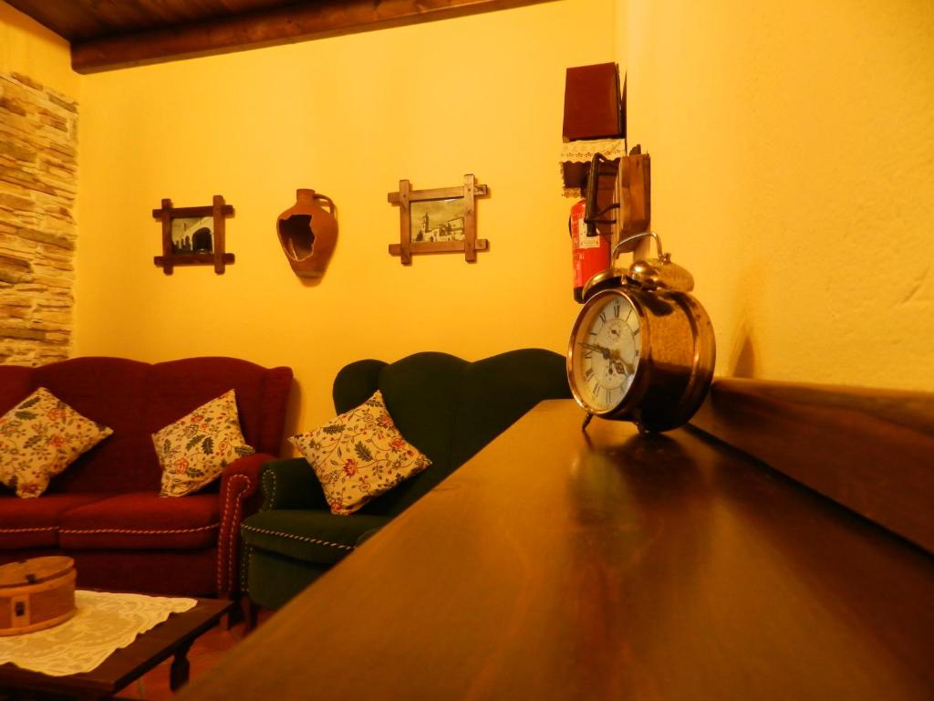 a living room with a couch and a clock on a table at Alojamiento Rural La Rabida 25 in Cumbres Mayores