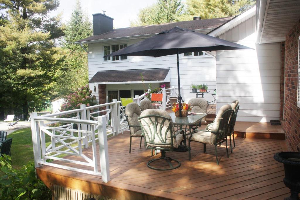 a deck with a table and chairs and an umbrella at Andante Gîte Bed and Breakfast in Cantley