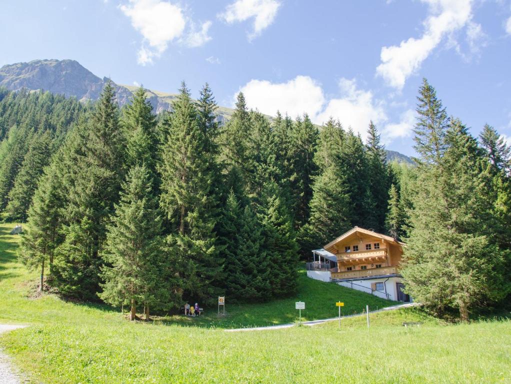 ein Haus inmitten eines Feldes mit Bäumen in der Unterkunft Family Lodge Maximilian in Tux