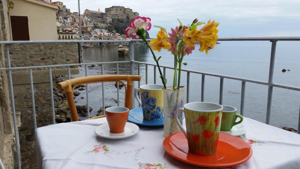 einen Tisch mit zwei Tassen und eine Vase mit Blumen in der Unterkunft Il Borgo in Scilla
