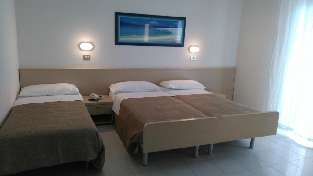 リミニにあるHotel Montiのベッド2台、壁掛けテレビが備わるホテルルームです。