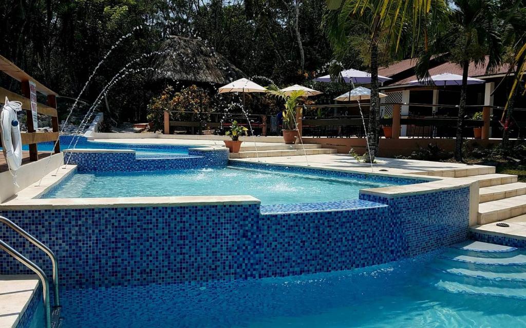 una piscina con piastrelle blu in un resort di The Log Cab-Inn a San Ignacio