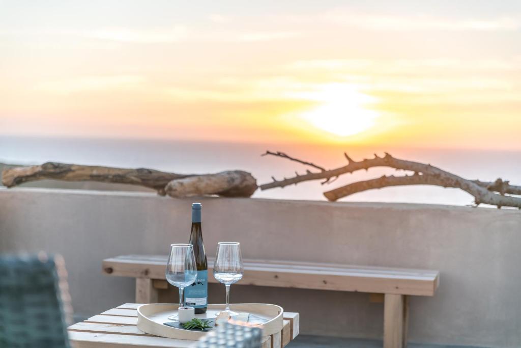 Una mesa con una botella de vino y dos copas. en Eco Soul Ericeira Guesthouse - Adults Only, en Ericeira