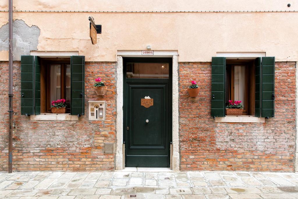 a brick building with a green door and two windows at Alla Vite Dorata in Venice