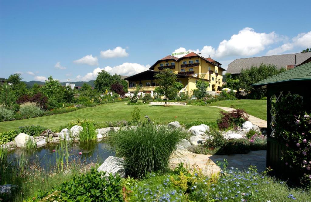 a house with a pond in the middle of a garden at Vitalhotel Marienhof in Velden am Wörthersee