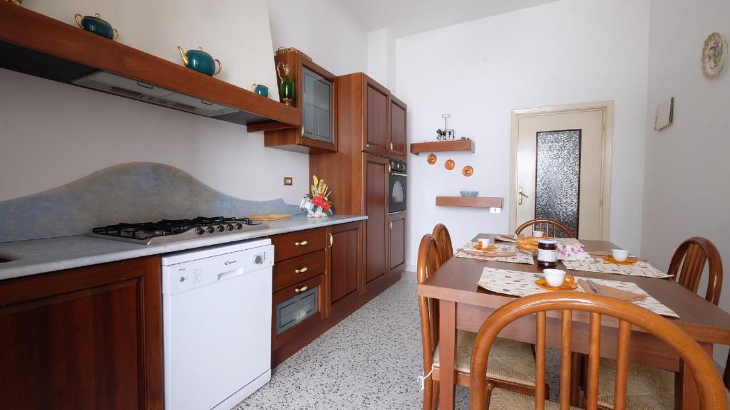 una cucina con tavolo e piano cottura bianco con forno di Orchidea 2 Pineto Vacanza a Pineto