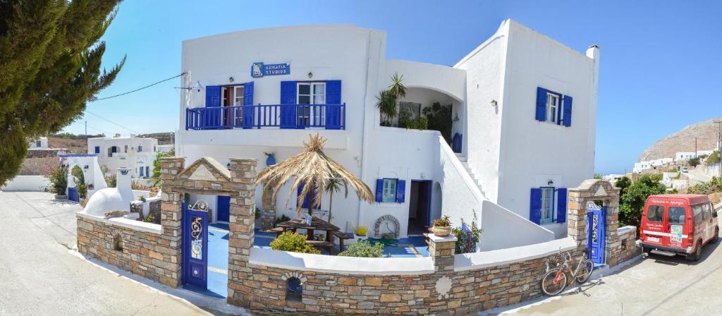 un bâtiment bleu et blanc avec un bus rouge dans l'établissement Evi's Studios, à Tholária