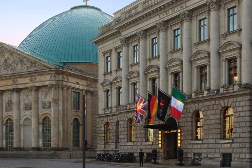 un gran edificio con banderas delante en Rocco Forte Hotel De Rome, en Berlín