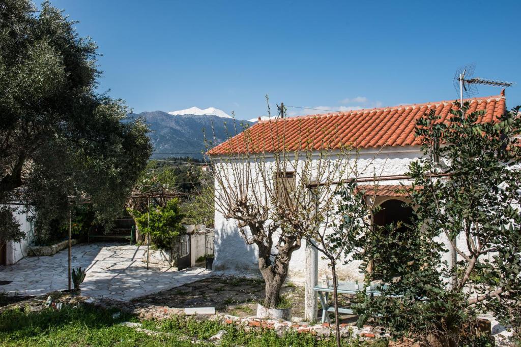 a white building with a red roof and trees at Traditional House in Alikampos