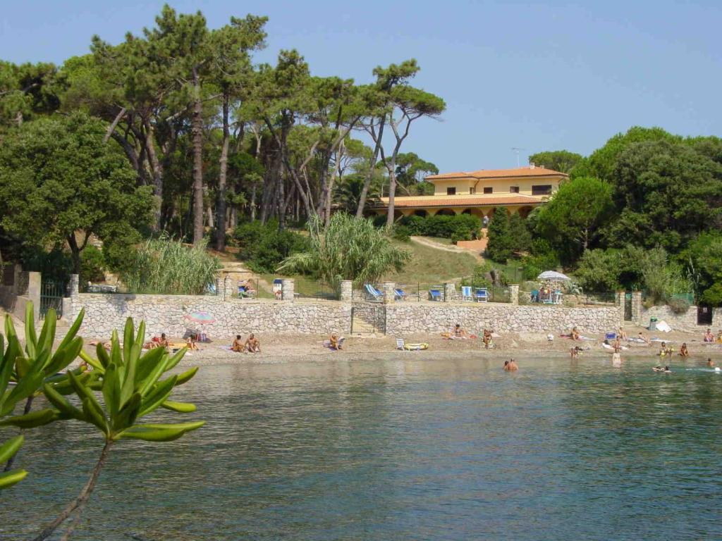 un groupe de personnes sur une plage près de l'eau dans l'établissement Residence Villa La Pineta, à Cavo