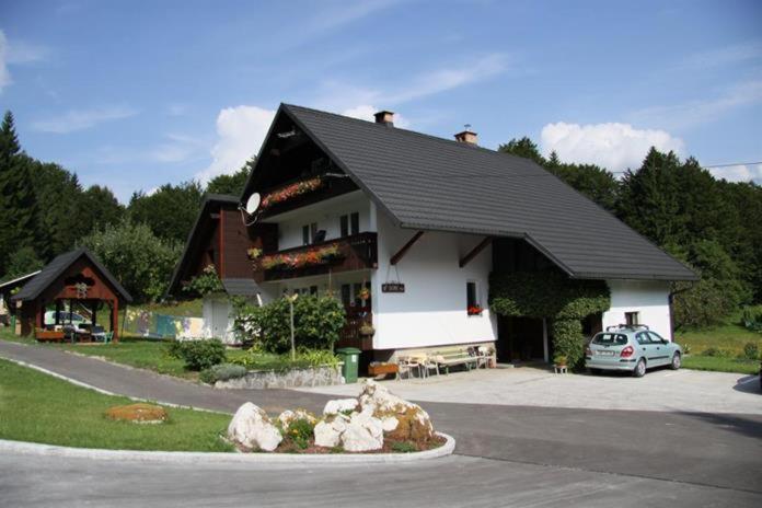 a house with a car parked in front of it at Apartments and rooms Cerkovnik in Bohinj