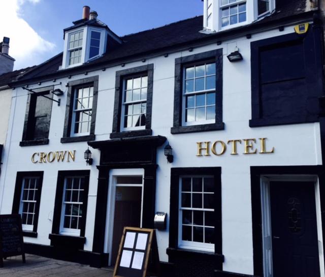 un hôtel blanc avec un panneau devant lui dans l'établissement The Crown Hotel, à Peebles