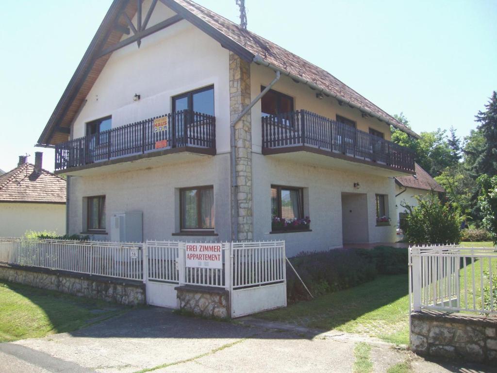 Casa blanca grande con balcones y valla en Gyöngyvirág Vendégház, en Balatonboglár