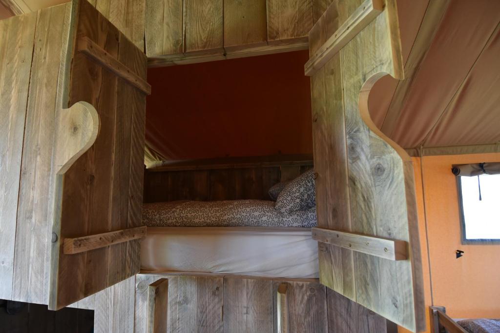 a bed in the middle of a room with wooden walls at Glamping Aan de Vleterbeke in Oostvleteren