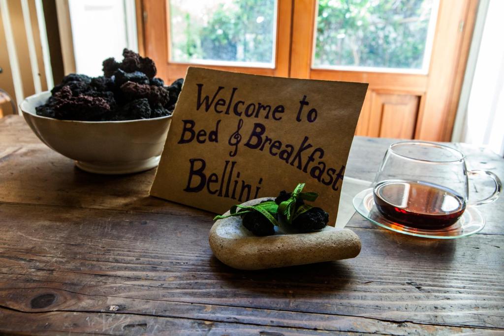 um sinal de boas-vindas na cama e pequeno-almoço numa mesa de madeira em Bellini Apartment em Catânia