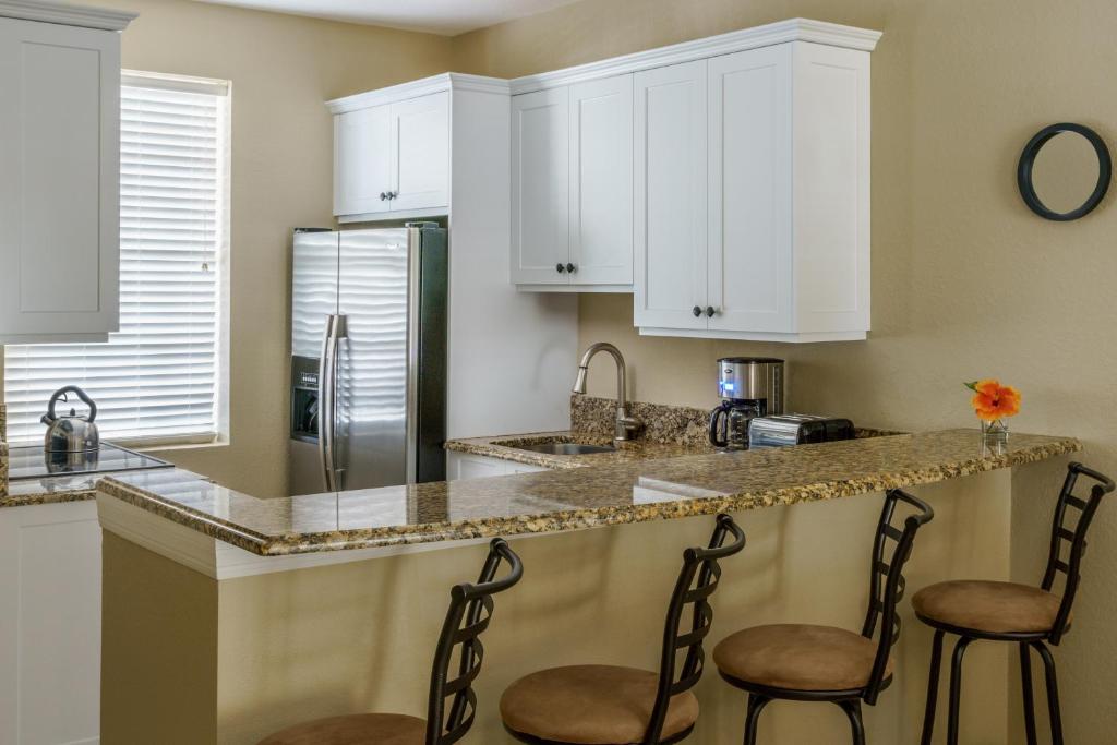 a kitchen with white cabinets and two chairs at a counter at Olde Marco Island Inn and Suites in Marco Island