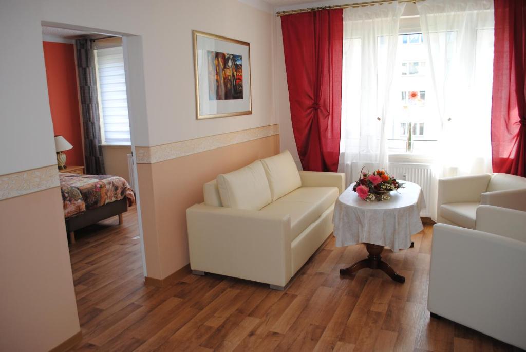 a living room with two white chairs and a table at Südwindappartement in Zwenkau