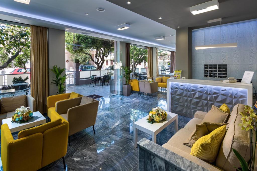 a lobby with couches and tables and yellow chairs at Olympia Hotel in Kos