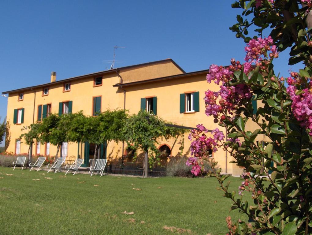 a building with chairs and flowers in front of it at Agriturismo Le Colombaie in Busseto